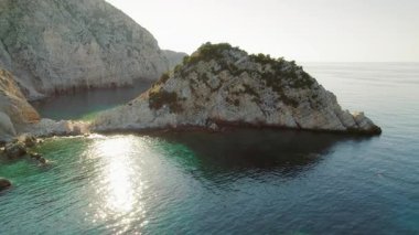 Kristal su ve sabah ışığıyla Kefalonia açıklarındaki Rocky adacığı..