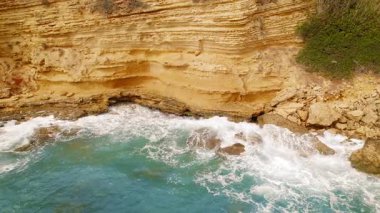 Yunanistan 'da yaz günü, açık turkuaz deniz sularıyla altın kayalık karşılaşması.