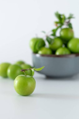 Beyaz arka planda seramik kasede yeşil erik meyvesi, hamile kadınların sevdiği meyve.