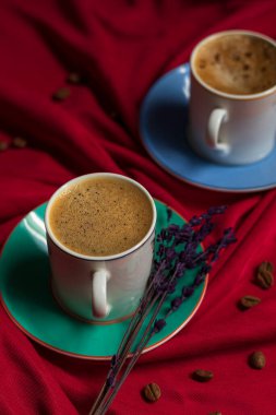 Kırmızı arka planda bol köpüklü Türk kahvesi ve kahve çekirdekleri