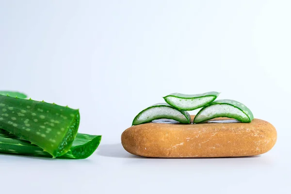 stock image Aloe Vera slices and spa stones, zen stone or pebble stone on wood table. Skin care concept.