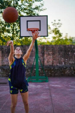 Sokak basketbolu oynayan bir kız basket topu yapmak için koşuyor.