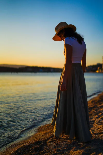 stock image athletic caucasian girl with straw hat looking at the sea on the sunset on the beach