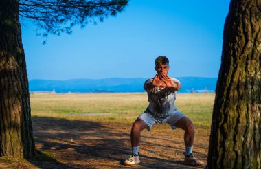 Adam parkın ortasında ve sahile yakın beyaz elbiseler üzerinde meditasyon yapıyor.