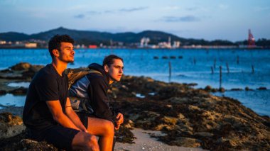 Genç bir çift gün batımını seyrediyor ve kendi eşyalarını düşünüyor. Siyah giyiyordu. Biri ciddi, diğeri ise gülümsüyor.