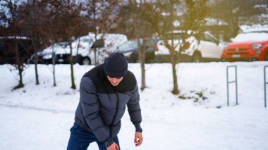 Hoş görünümlü erkek model, mutlu bir şekilde uzaklarda, iyi bir ruh halinde, açık havada duruyor. Güzel kış manzarası