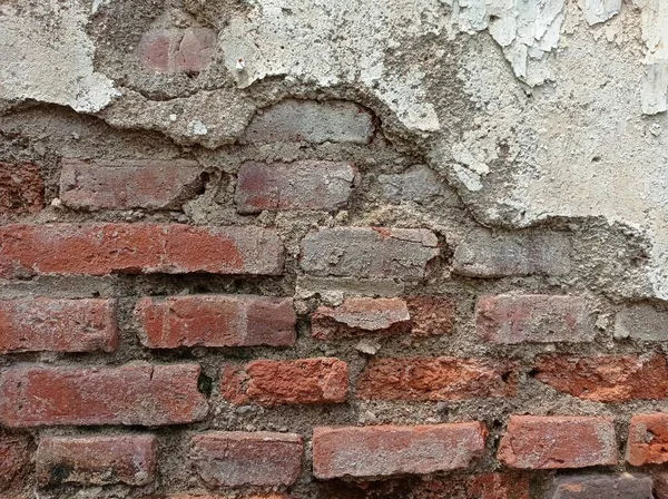 stock image Old broken wall revealing the bricks in it. Damage illustration on wall.