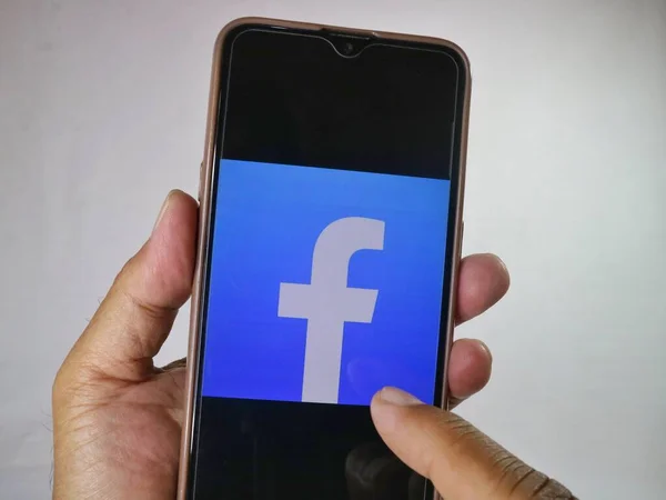 Cep telefonunu parmaklarıyla tutarak ekrandaki Facebook logosuna dokun. 