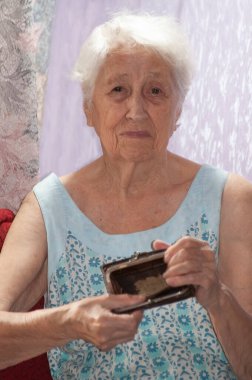 Yaşlı bir kadın ahşap şarap masasında boş bir çanta tutuyor. Emeklilikteki yoksulluk kavramı. Küresel Aşırılık. Para yok. Yardım edin..