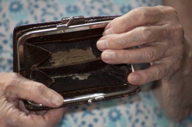 Yaşlı bir kadın ahşap şarap masasında boş bir çanta tutuyor. Emeklilikteki yoksulluk kavramı. Küresel Aşırılık. Para yok. Yardım edin..