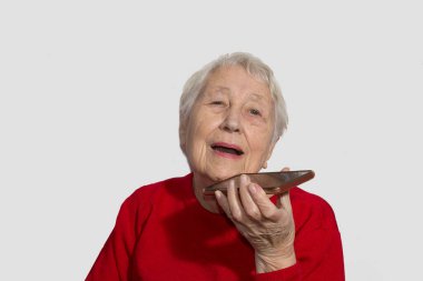 Sesi tanıma işlevini cep telefonunda kullanan çekici yaşlı bir kadın. Elektronik alet tutan, sesli mesaj gönderen ya da internetten mesaj gönderen son sınıf öğrencisi bir kadın.