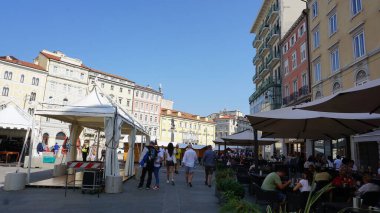 Trieste, İtalya - 1 Ekim 2023: İnsanlar eski ve renkli Akdeniz evlerinin cepheleriyle Trieste sokaklarına dökülüyor. Trieste, İtalya