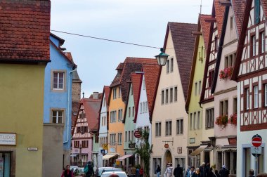 Rothenburg ob der Tauber, Almanya - 20 Ekim 2023: İnsanlar Rothenburg ob der Tauber 'deki tarihi binaların yakınına gidiyorlar - Almanya' nın eski güçlendirilmiş kenti.