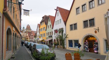 Rothenburg ob der Tauber, Almanya - 20 Ekim 2023: İnsanlar Rothenburg ob der Tauber 'deki tarihi binaların yakınına gidiyorlar - Almanya' nın eski güçlendirilmiş kenti.