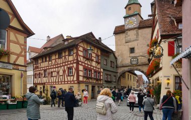 Rothenburg ob der Tauber, Almanya - 20 Ekim 2023: İnsanlar Rothenburg ob der Tauber 'deki tarihi binaların yakınına gidiyorlar - Almanya' nın eski güçlendirilmiş kenti.