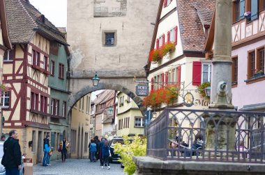 Rothenburg ob der Tauber, Almanya - 20 Ekim 2023: İnsanlar Rothenburg ob der Tauber 'deki tarihi binaların yakınına gidiyorlar - Almanya' nın eski güçlendirilmiş kenti.