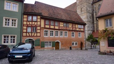 Rothenburg ob der Tauber, Almanya - 20 Ekim 2023: İnsanlar Rothenburg ob der Tauber 'deki tarihi binaların yakınına gidiyorlar - Almanya' nın eski güçlendirilmiş kenti.