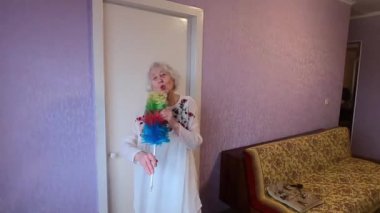 Komik son sınıf 90 'ların kadını toz süpürgesinde şarkı söylüyor. Mutlu yaşlı kadın şarkıcı gibi şarkı söylüyor. Evde dans ediyor.