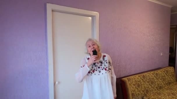 上世纪90年代有趣的老年女子在梳头时歌唱 快乐的老太太像歌唱家一样在家里欢快地跳舞 — 图库视频影像