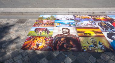 Rimini, İtalya - 25 Haziran 2024: Afrikalı bir sokak ressamı Rimini, İtalya 'daki bir meydanda renkli resimlerini çiziyor