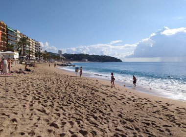 Lloret de mar, İspanya - 30 Eylül 2024: İnsanlar Lloret De Mar plajında dinleniyor. Güneşli bir günde Katalonya 'nın Costa Brava plajı