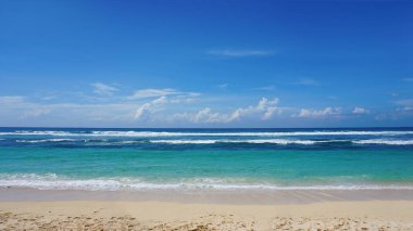 Melasti Plajı güneşli bir günde beyaz kum ve mavi deniz suyuyla güzeldir.