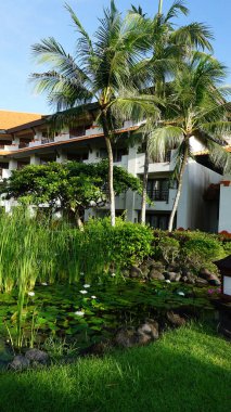 Nusa Dua, Bali, Endonezya - 18 Ocak 2025: Nusa Dua, Bali, Endonezya 'daki Grand Hyatt Bali tatil köyündeki otel binası ve tropikal ağaçlar.