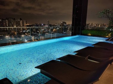 Singapur - 21 Ocak 2025: 21 Ocak 2025 tarihinde Singapur 'un Uzak Doğu Konukseverliği tarafından Singapur' daki The Clan Hotel 'de sonsuzluk yüzme havuzu. Havuzun modern iş gökdelenlerinin panoramik manzarası var.