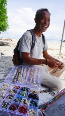 Gili Trawangan, Endonezya -- 16 Ocak 2025: Yerel gülen adam -bali inci satıcısı Gili Trawangan, Endonezya sahilinde 16 Ocak 2025