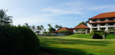 Nusa Dua, Bali, Endonezya - 18 Ocak 2025: Nusa Dua, Bali, Endonezya 'daki Grand Hyatt Bali tatil köyündeki otel binası ve tropikal ağaçlar.
