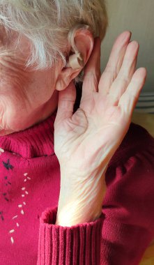 Orta yaşlı kadın evde işitme cihazı kullandığından emin bir şekilde gülümsüyor.