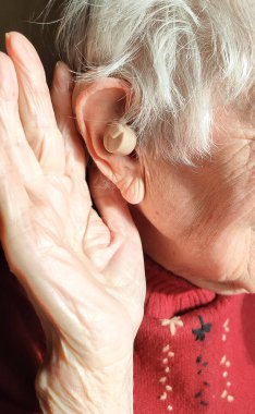 Orta yaşlı kadın evde işitme cihazı kullandığından emin bir şekilde gülümsüyor.