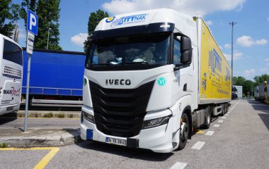 Bari, İtalya - 10 Mayıs 2025: Beyaz Iveco arabası şehir caddesinde. Iveco 'nun park yerinde ağır yük kamyonu var. Sağ ön görünüm.