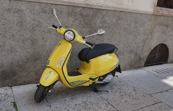 Bari, İtalya - 10 Mayıs 2025: Sarı Vespa Primavera Sprint 125, bir şehir caddesinde belirlenmiş park yerine park etmiş bir scooter.,