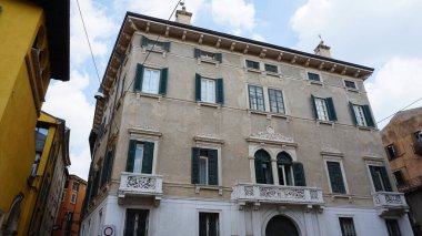 İtalya, Verona 'da ortaçağ duvarının balkonunda çiçekleri olan güzel geleneksel İtalyan binası.