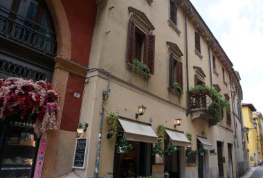 Verona, İtalya - 12 Mayıs 2025: Ortaçağ duvarı balkonunda çiçekli güzel geleneksel İtalyan binası