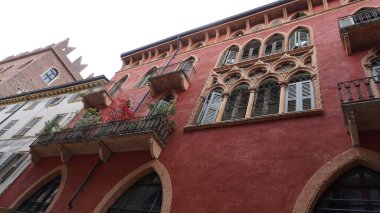 İtalya, Verona 'da ortaçağ duvarının balkonunda çiçekleri olan güzel geleneksel İtalyan binası.