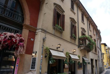 Verona, İtalya - 12 Mayıs 2025: Ortaçağ duvarı balkonunda çiçekli güzel geleneksel İtalyan binası