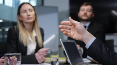 Ofiste toplantının ortasında el kol hareketi yapan işadamı, arka plandaki iş arkadaşlarını bulanık bir şekilde projeyi tartışıyor, fikirleri paylaşıyor, yakın çekim yapıyor. Liderlik kavramı