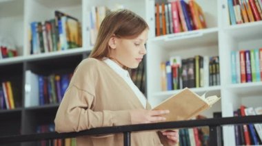 Sıradan giyinen liseli kızlar kitaplıkların yanında durup kitap okurlar, metal parmaklıklara yaslanırlar. Düşük açılı yay, kütüphanede edebiyatın tadını çıkaran küçük bir okuyucuyu vurdu. Eğitim kavramı