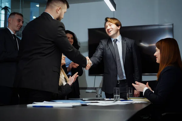 Top managers signing contract and shaking hands in office, members of meeting clapping hands. Business partners making deal. Concept of collaboration