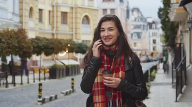 Kahve fincanı olan neşeli esmer kadın, deri ceketli, kareli eşarplı telefonda konuşan, bulanık eski bina geçmişi olan. Genç bir bayan şehirde taksi bekliyor. İletişim kavramı