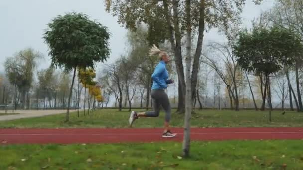 Повільний Рух Підходить Жінці Синій Спортивній Куртці Біжить Трасі Осінньому — стокове відео