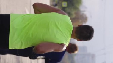 Boş şehir yolunda maraton koşucuları, sarı bluzlu adama odaklanın. Yavaş çekim sporcuları spor müsabakalarına katılıyor. Sağlıklı yaşam tarzı kavramı