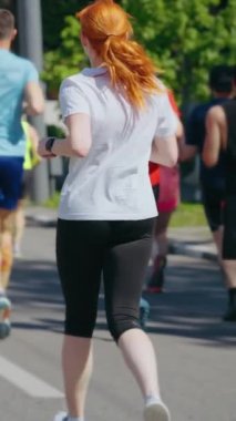 Spor giyim maratonunda ağır çekimde koşan insanlar, kızıl saçlı kadına odaklanın. Atış sonrası atletizm koşucusu sokak yarışına katılıyor.