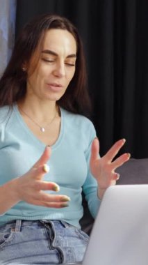 Dikey Ekran: Kanepede oturan ve dizüstü bilgisayarında web kamerasıyla konuşan neşeli bir kadın. Salgın sırasında evde otururken iş adamının online toplantısını büyüt. Uzak çalışma kavramı