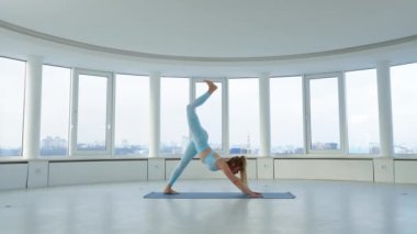 Genç, sarışın bir kadın yoga stüdyosunda tek bacaklı köpek ve çarpık savaşçı pozları veriyor. Yogi dişisi üç bacaklı köpek yapıyor, egzersiz yapıyor. Sağlıklı yaşam tarzı kavramı
