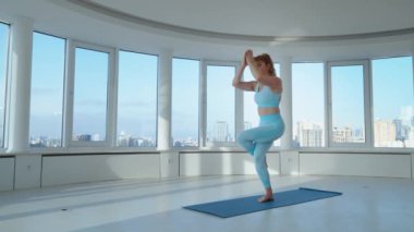 Atkuyruklu, mavi spor kıyafetli, yoga stüdyosunda Kartal pozu veren sarışın genç bir kadın. Yogi dişisi Garudasana yapıyor, egzersizleri dengeliyor. Sağlıklı yaşam tarzı kavramı
