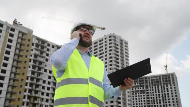 Civil Engineer Wearing Hard Hat Safety Vest Using Clipboard Talking — Vídeo de Stock