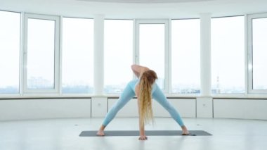 Yetişkin sarışın kadın yoga stüdyosunda geniş bacaklı kıvrım pozu veriyordu. Yogi dişisi Prasarita Padottanasana. Sağlıklı yaşam tarzı kavramı